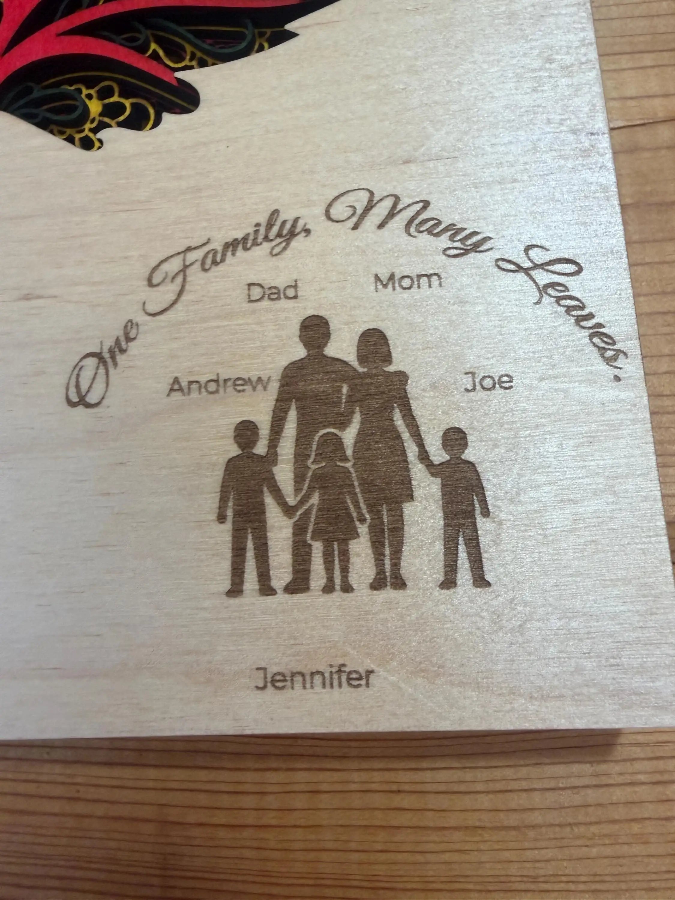 Custom laser-cut wood family art with 'One Family, Many Leaves' engraving and personalized names.