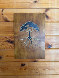 Layered wood art of a tree with roots, handcrafted laser-cut wall decor on rustic wood background