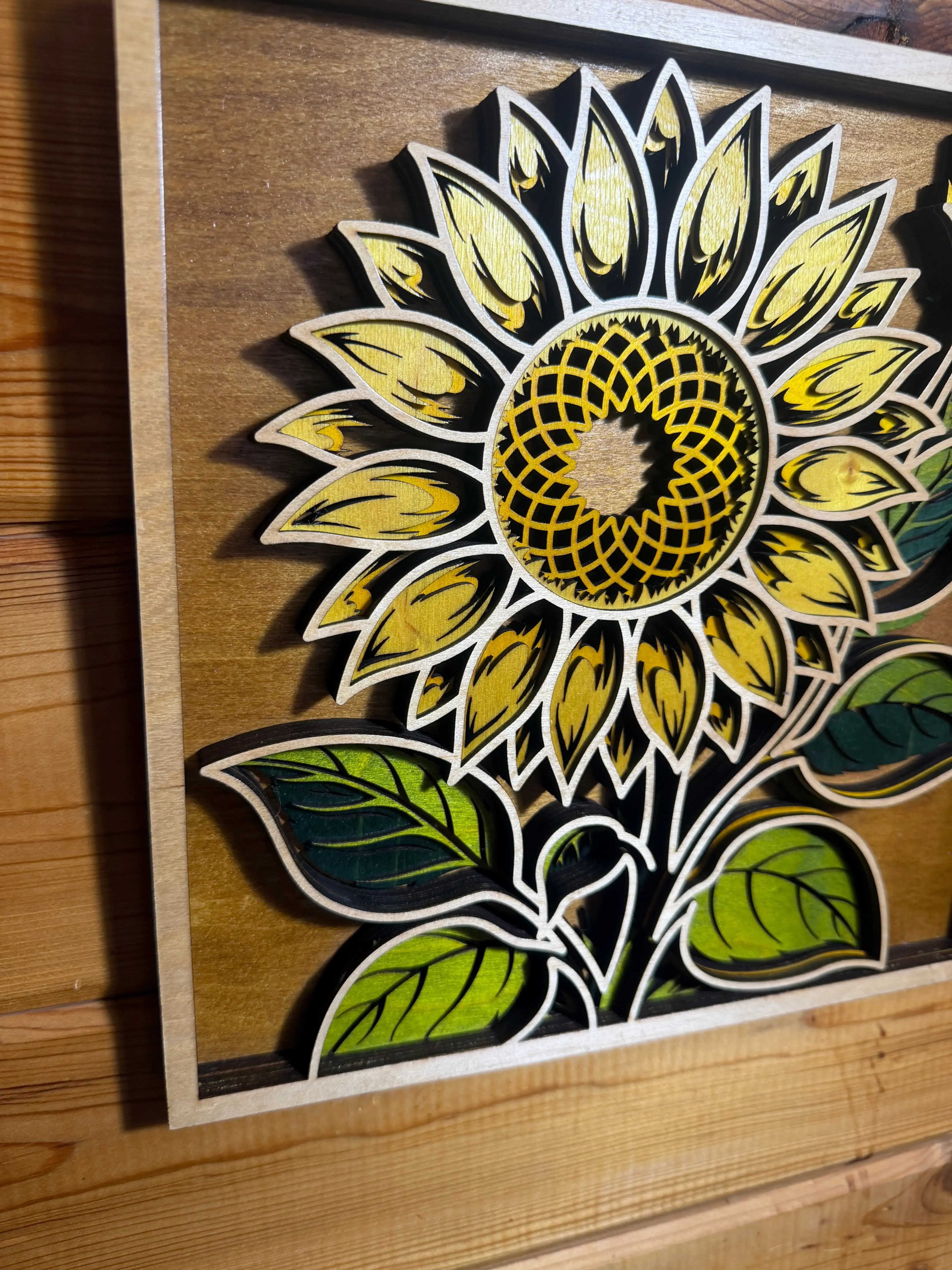 Layered wood sunflower art with vibrant yellow petals and green leaves, handcrafted decor