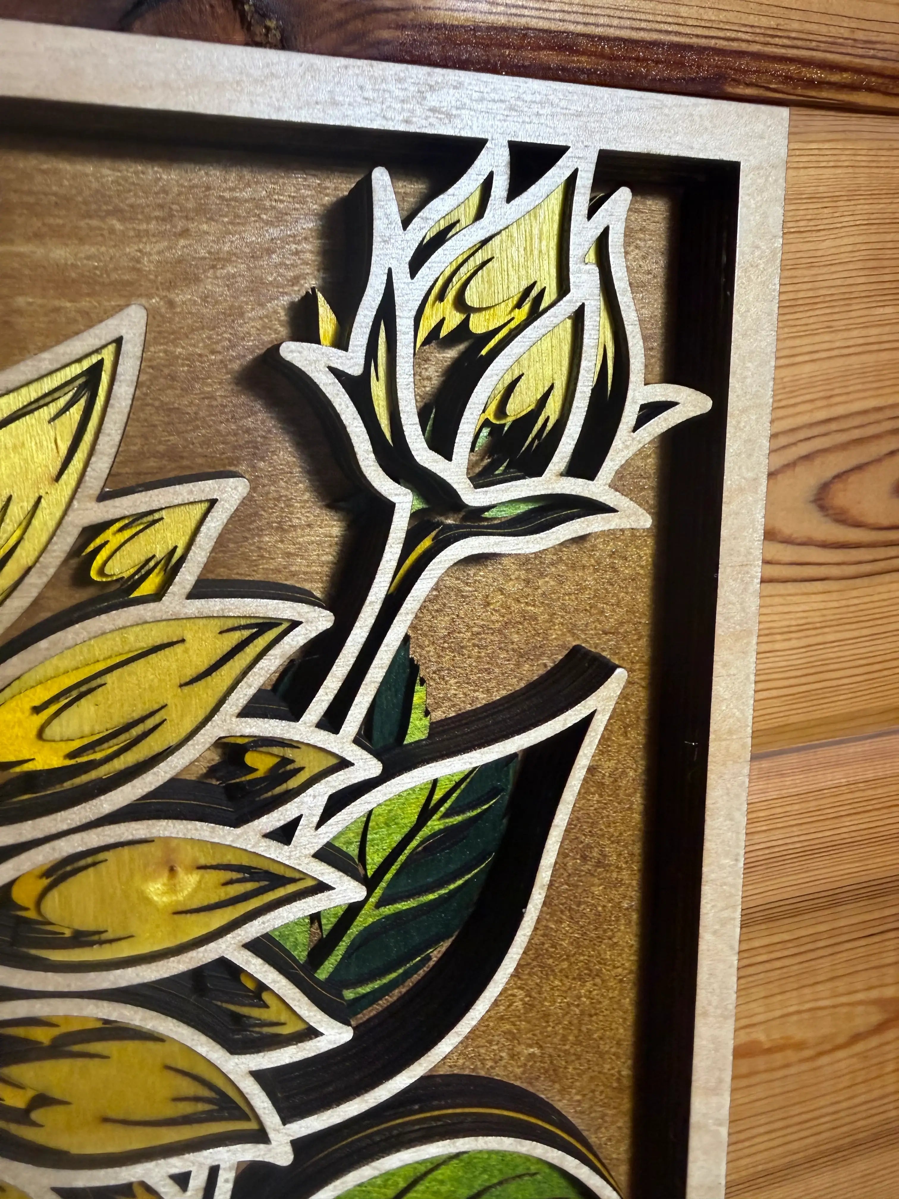 Layered wood art featuring sunflower design with yellow petals and green leaves, handcrafted decor