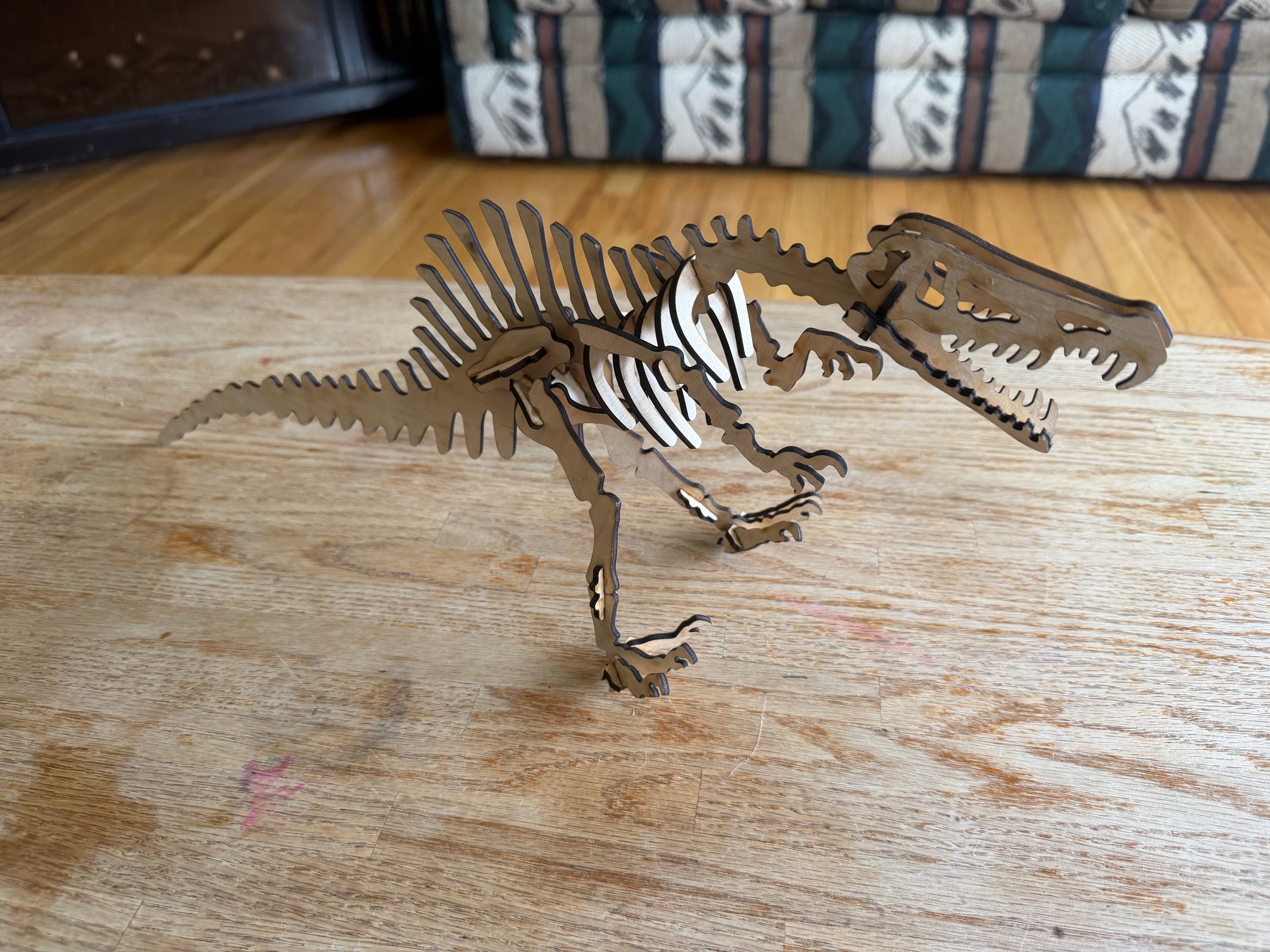 Laser-cut wooden dinosaur skeleton art on rustic table, handcrafted layered wood decor