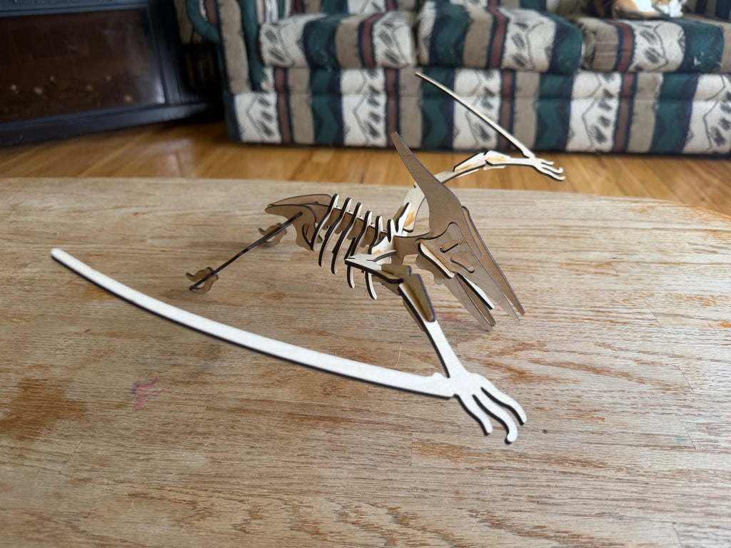 Laser-cut wooden dinosaur skeleton art piece on a rustic table, handcrafted decor