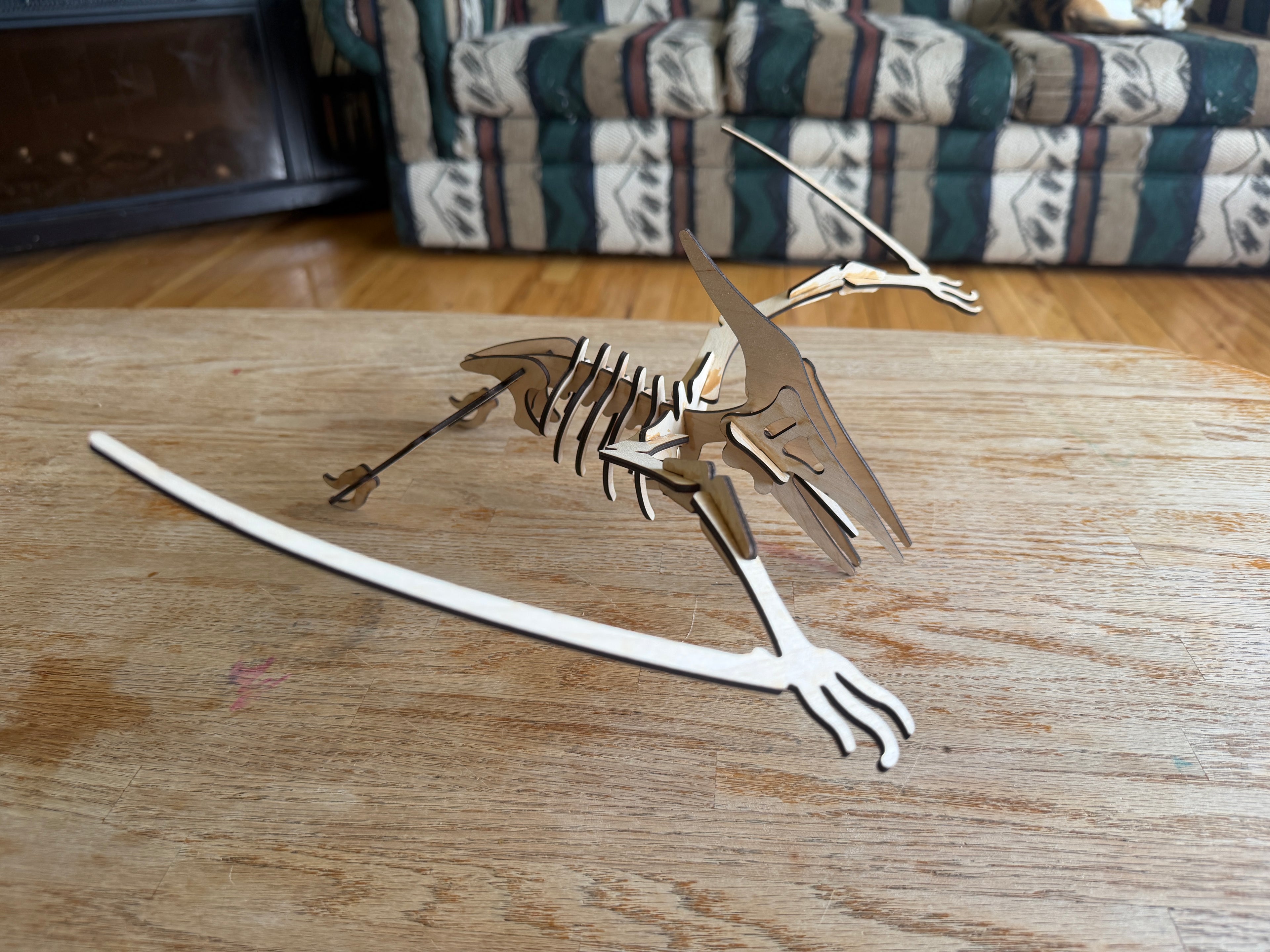 Laser-cut wooden dinosaur skeleton art piece on a rustic table, handcrafted decor