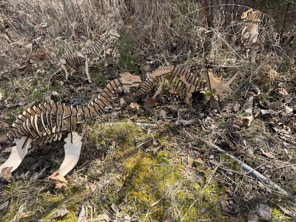 Handcrafted wooden dinosaur skeletons in a forest setting, showcasing layered wood art.