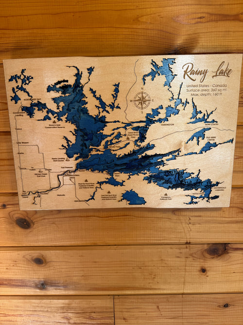 Layered wood map of Rainy Lake, USA-Canada border, with blue water depths and engraved locations, rustic decor.