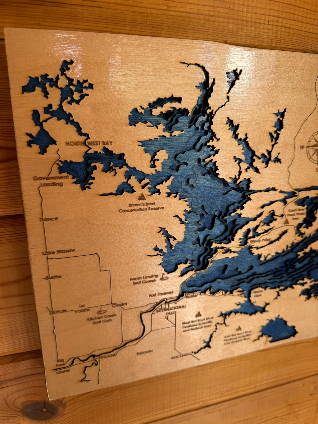Wooden map with blue water features on a wooden surface