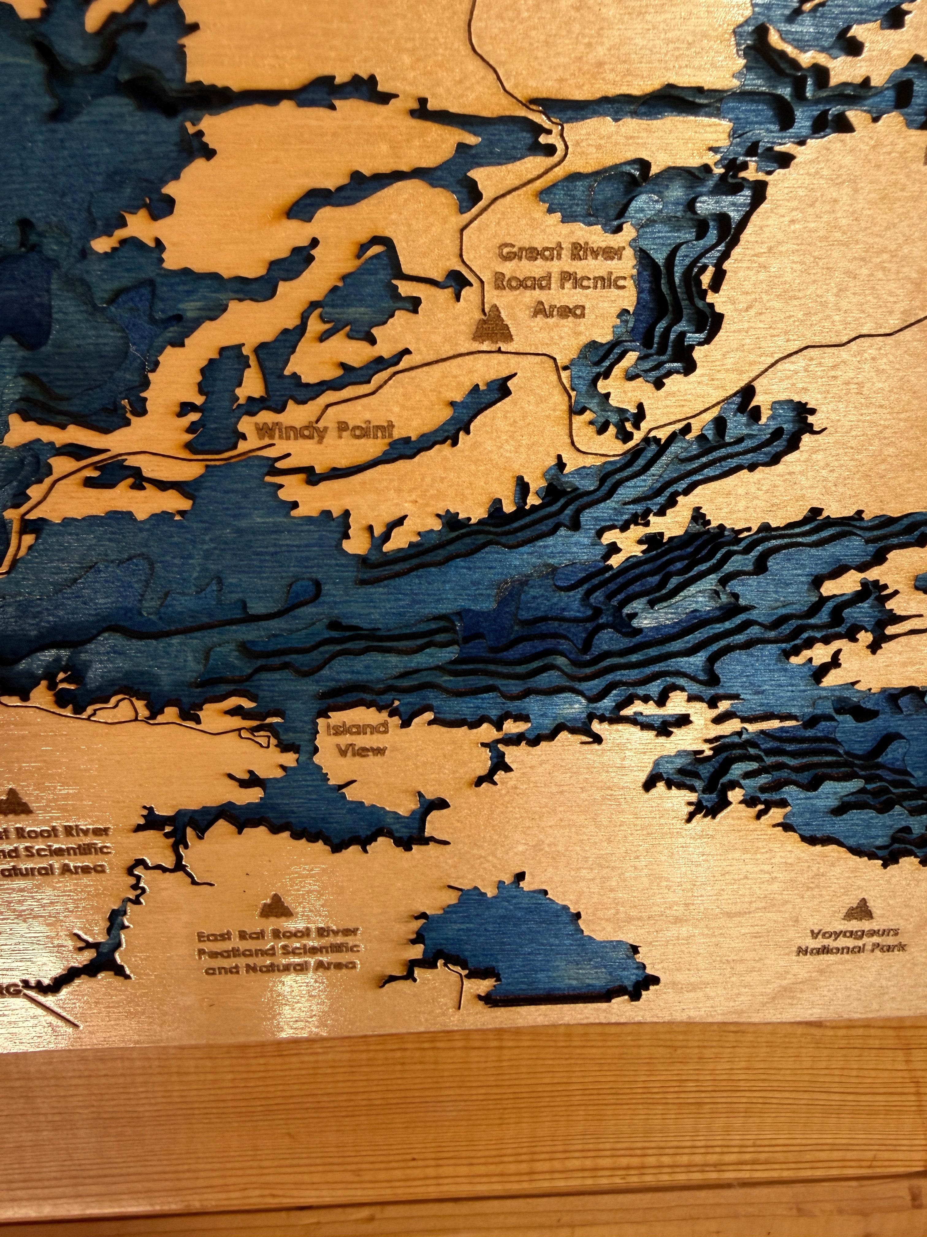 Wooden topographic map with embossed waterways and text