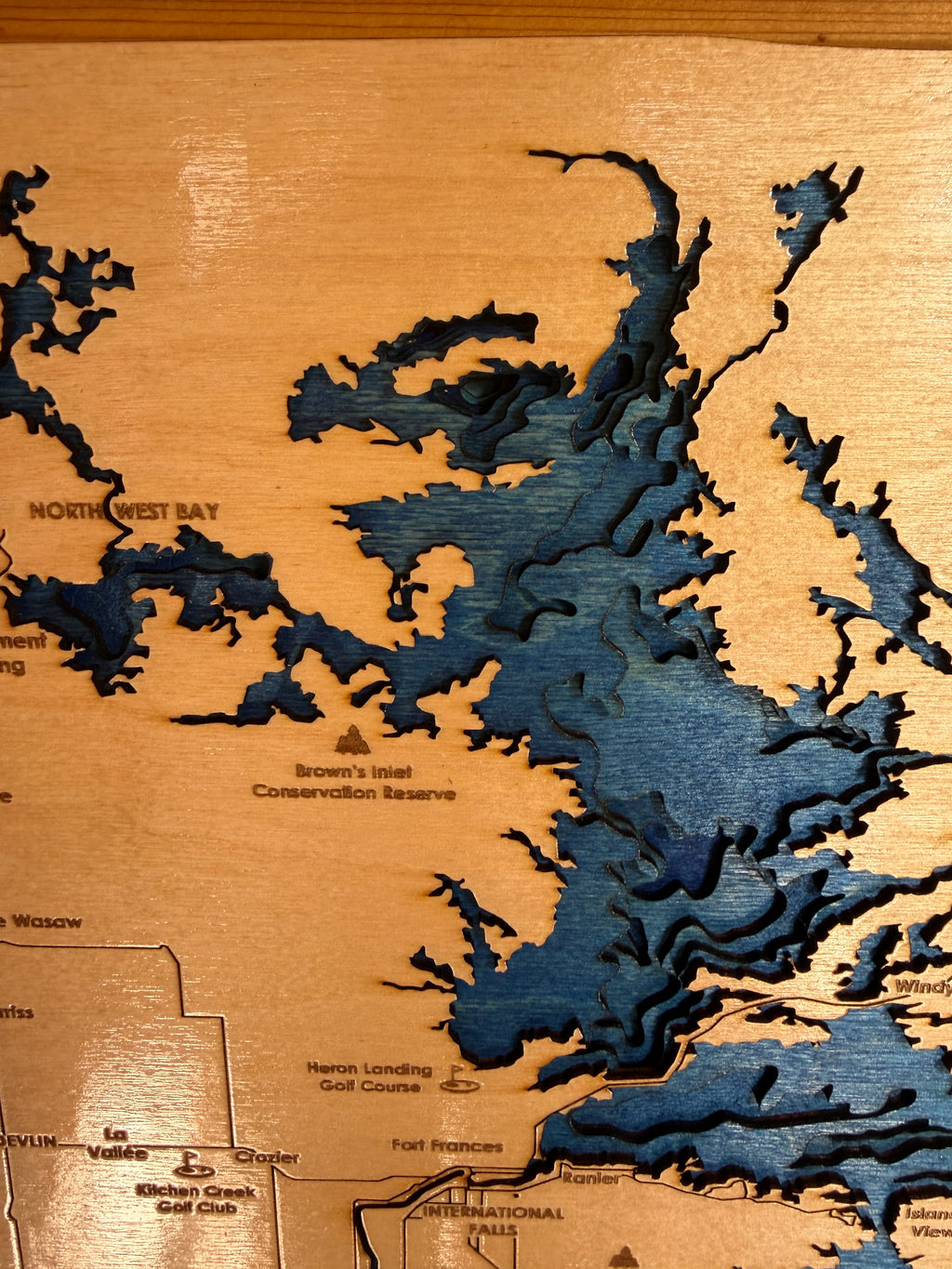 Wooden map with laser-cut topography, showing water bodies and land features.