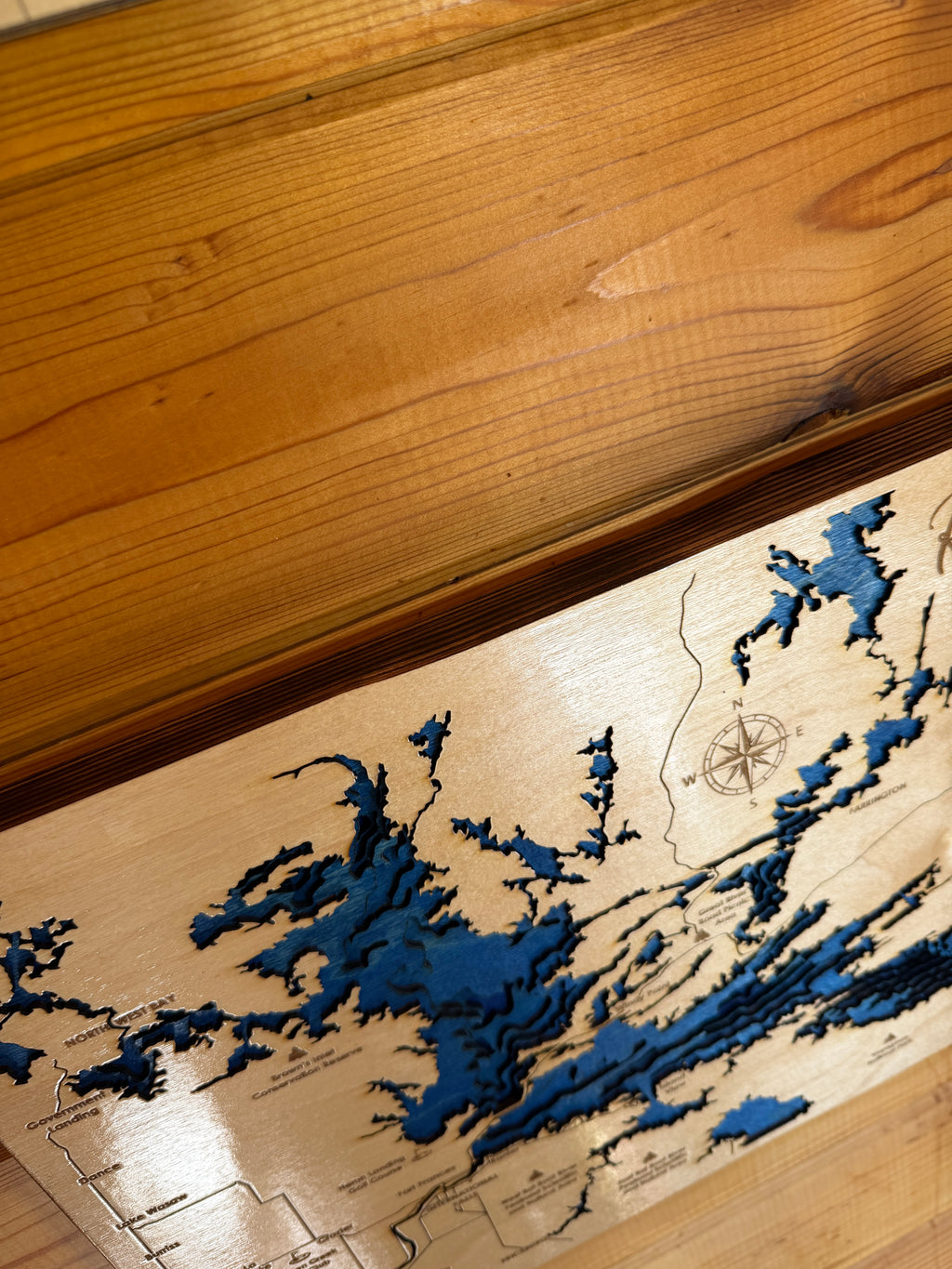 Wooden map with blue water features on a wooden surface