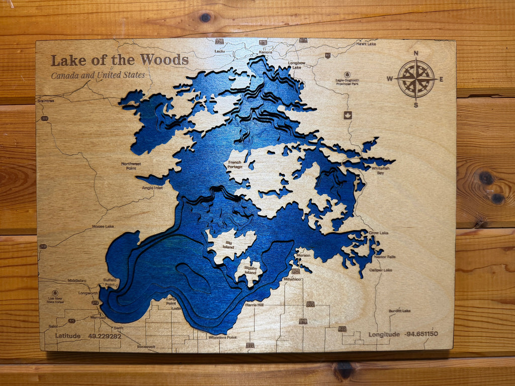 Layered wood art map of Lake of the Woods, Canada and US, with blue water details and compass rose