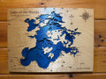 Layered wood art map of Lake of the Woods, Canada and US, with blue water details and compass rose