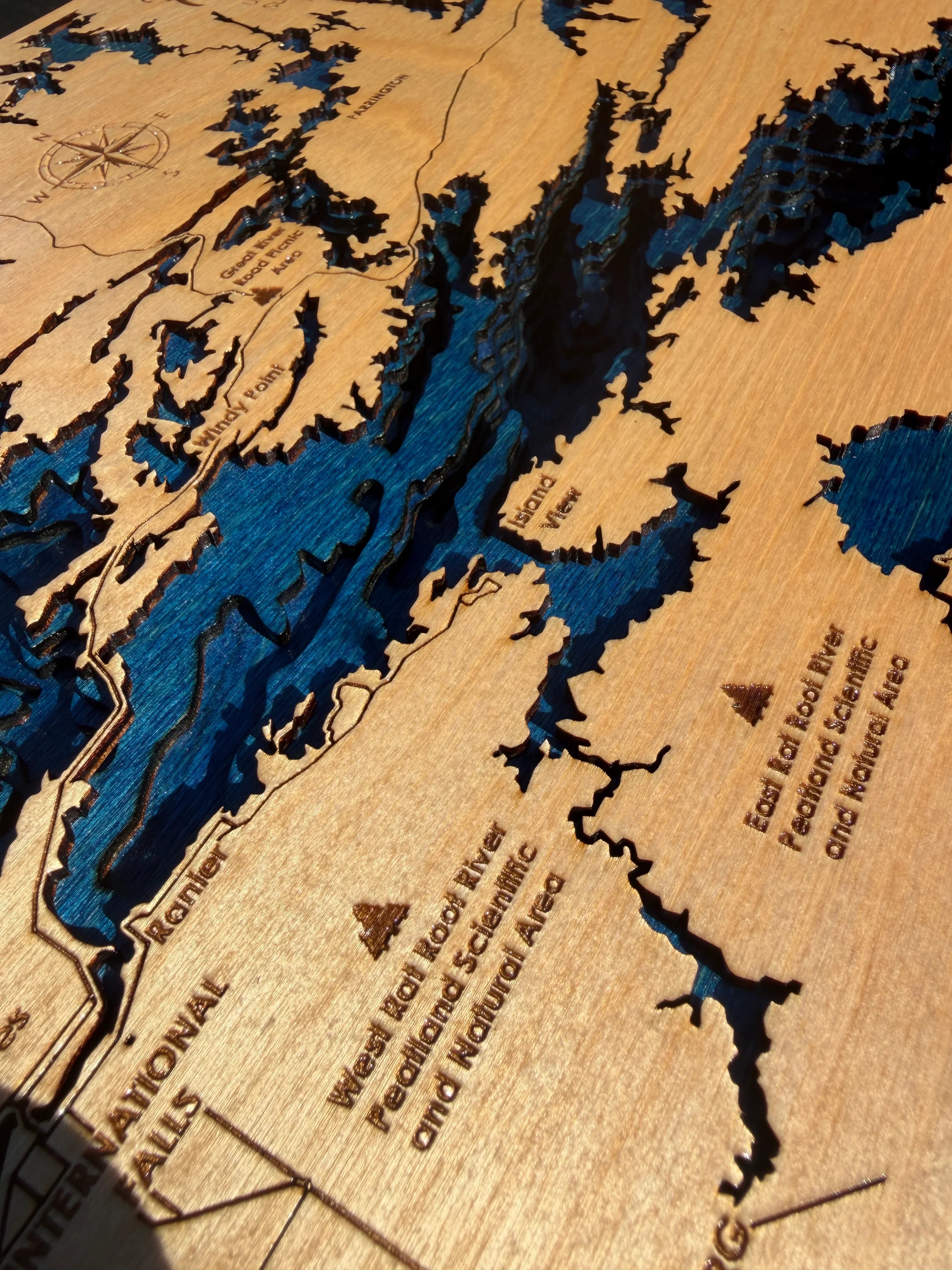 Handcrafted layered wood lake map with blue water, engraved locations, and natural wood grain texture