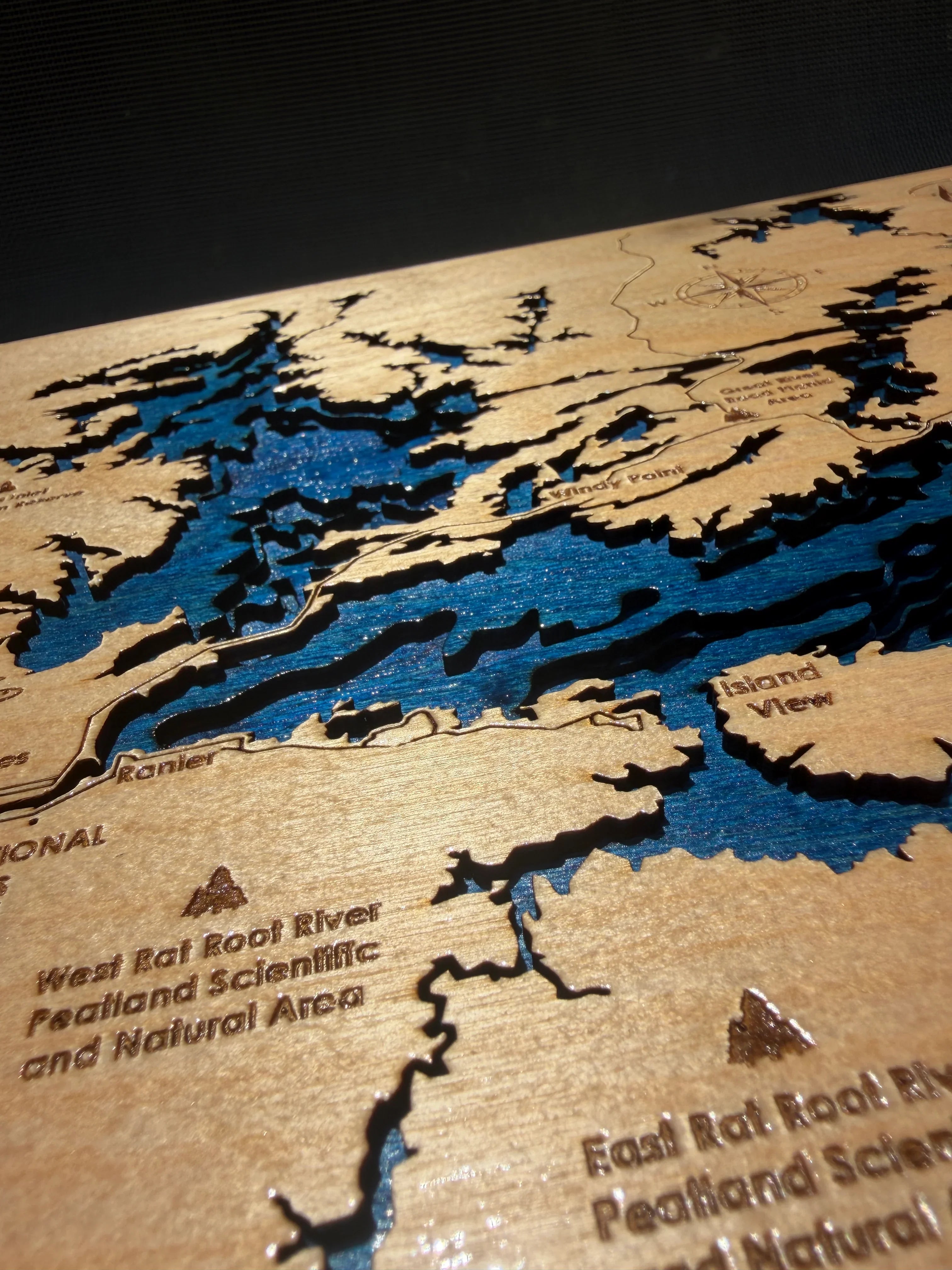 Handcrafted layered wood lake map with blue water details, laser-cut for rustic home decor.