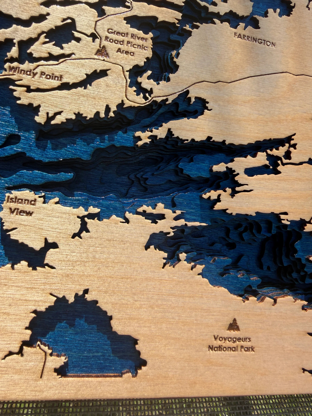 Layered wood map of Rainy River area with blue water depth layers, featuring Windy Point, Island View, and Voyageurs National Park.