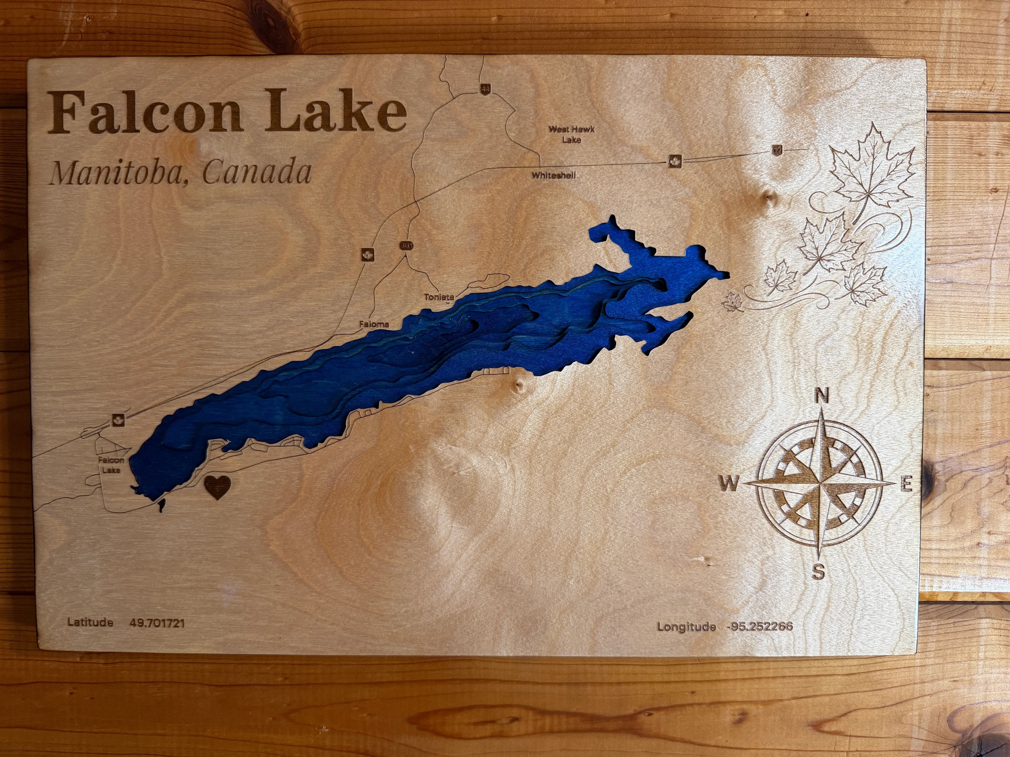 Layered wood art map of Falcon Lake, Manitoba, Canada with blue water design and compass rose
