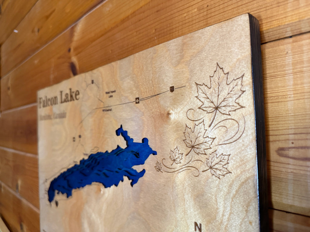 Handcrafted Falcon Lake map art with layered wood, blue lake cutout, and engraved maple leaves for rustic home decor.