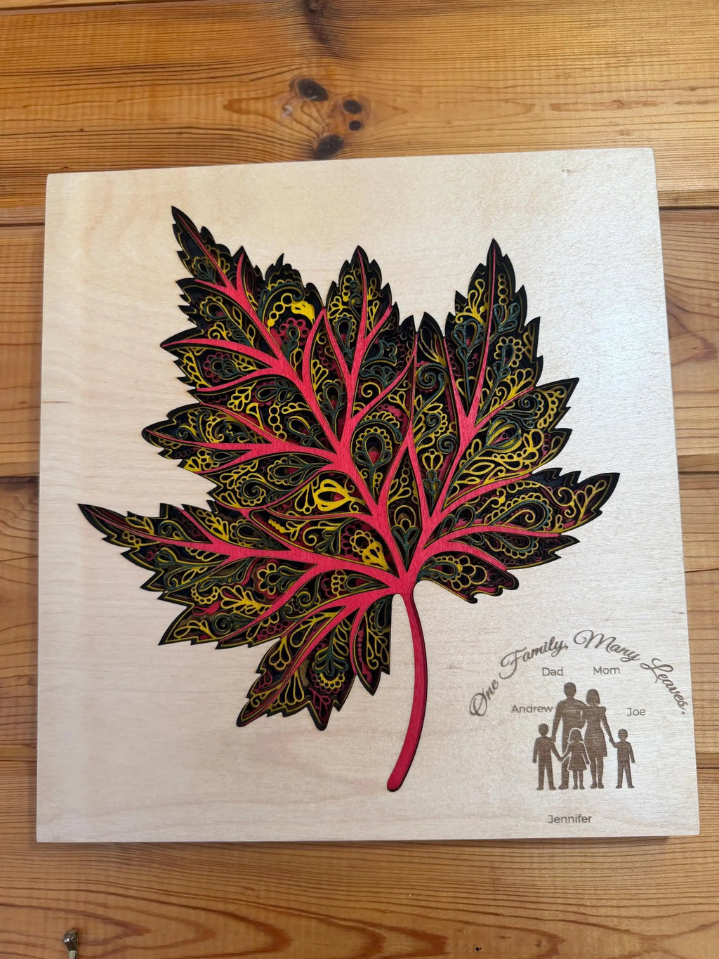 Custom layered wood art maple leaf with intricate patterns and family names, handcrafted decor