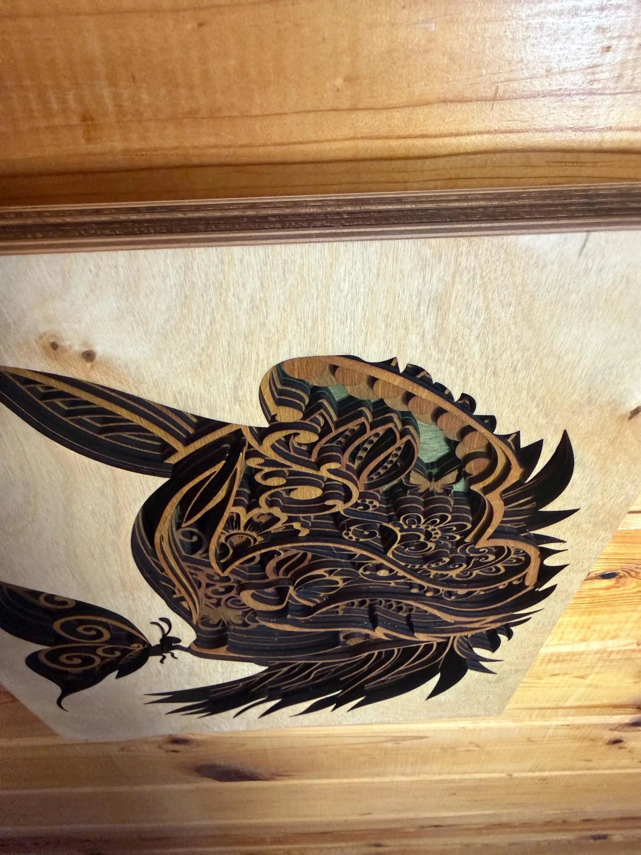 Intricate laser-cut wood art featuring a detailed bird design with layered patterns and natural wood tones.