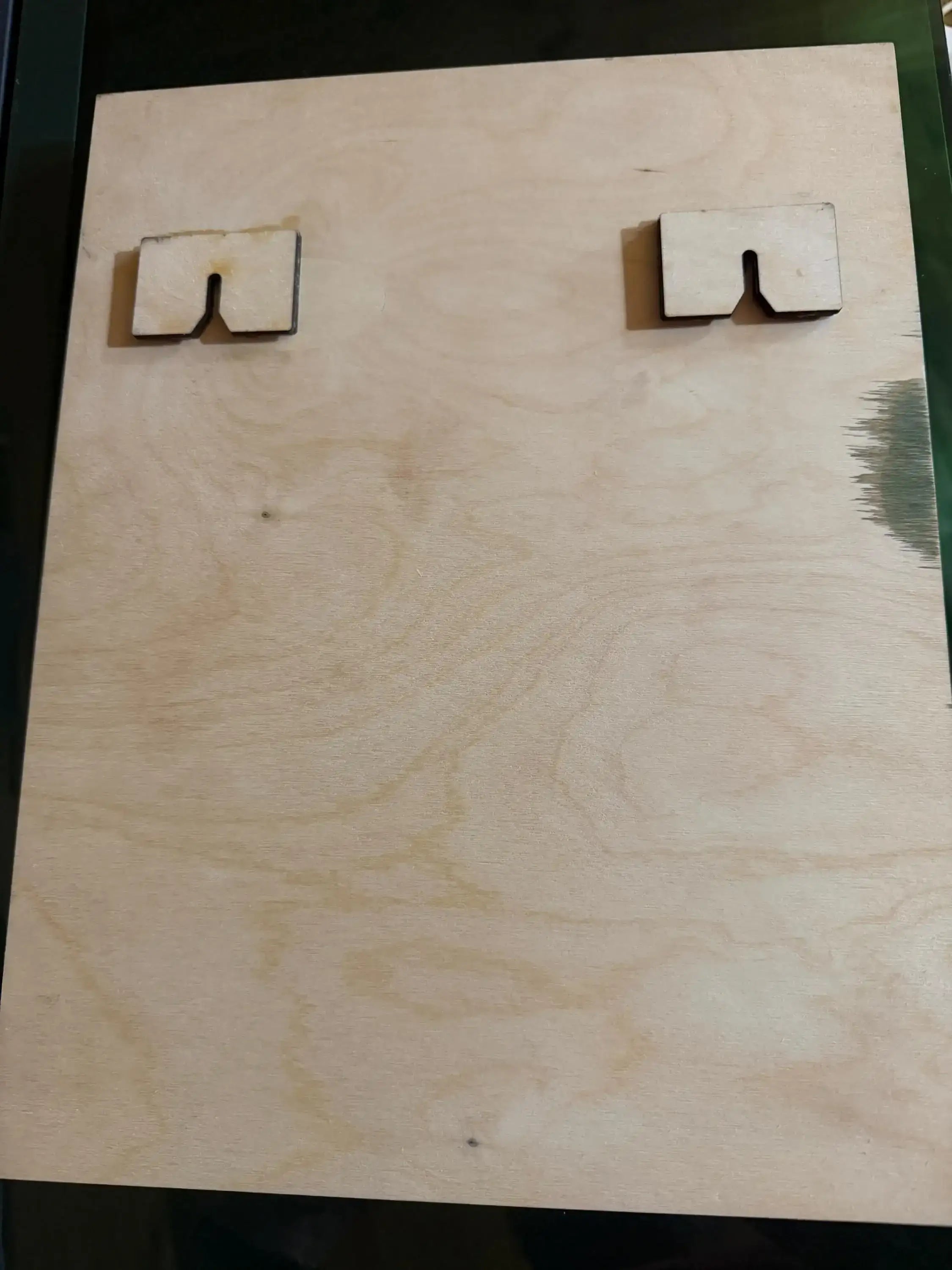 Laser-cut wooden pieces with notched edges on a plywood board, showcasing handcrafted wood art.