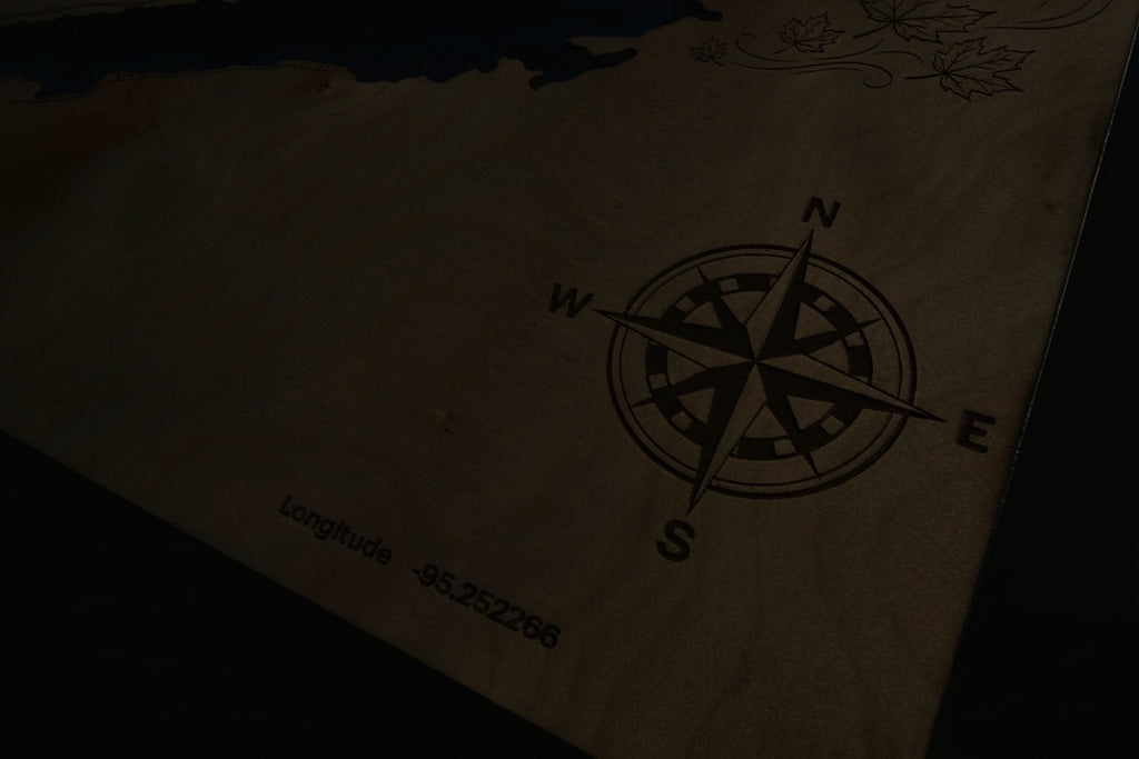 Laser-cut wooden lake map with engraved compass rose and coordinates, featuring layered depth design and maple leaf details.