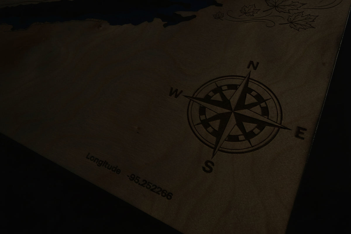 Laser-cut wooden lake map with engraved compass rose and coordinates, featuring layered depth design and maple leaf details.