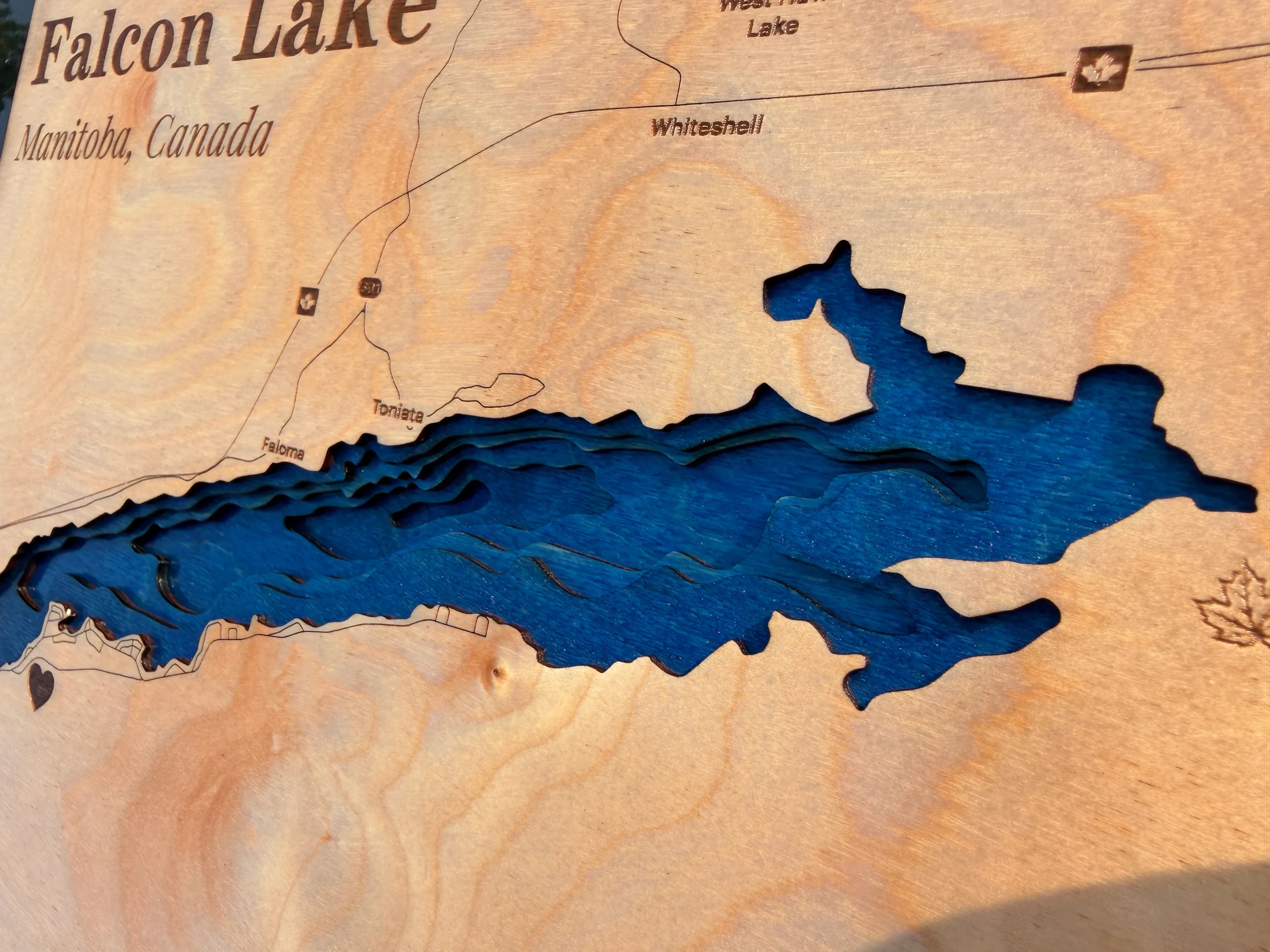 Layered wood art map of Falcon Lake, Manitoba, Canada with blue depth layers and laser-cut details
