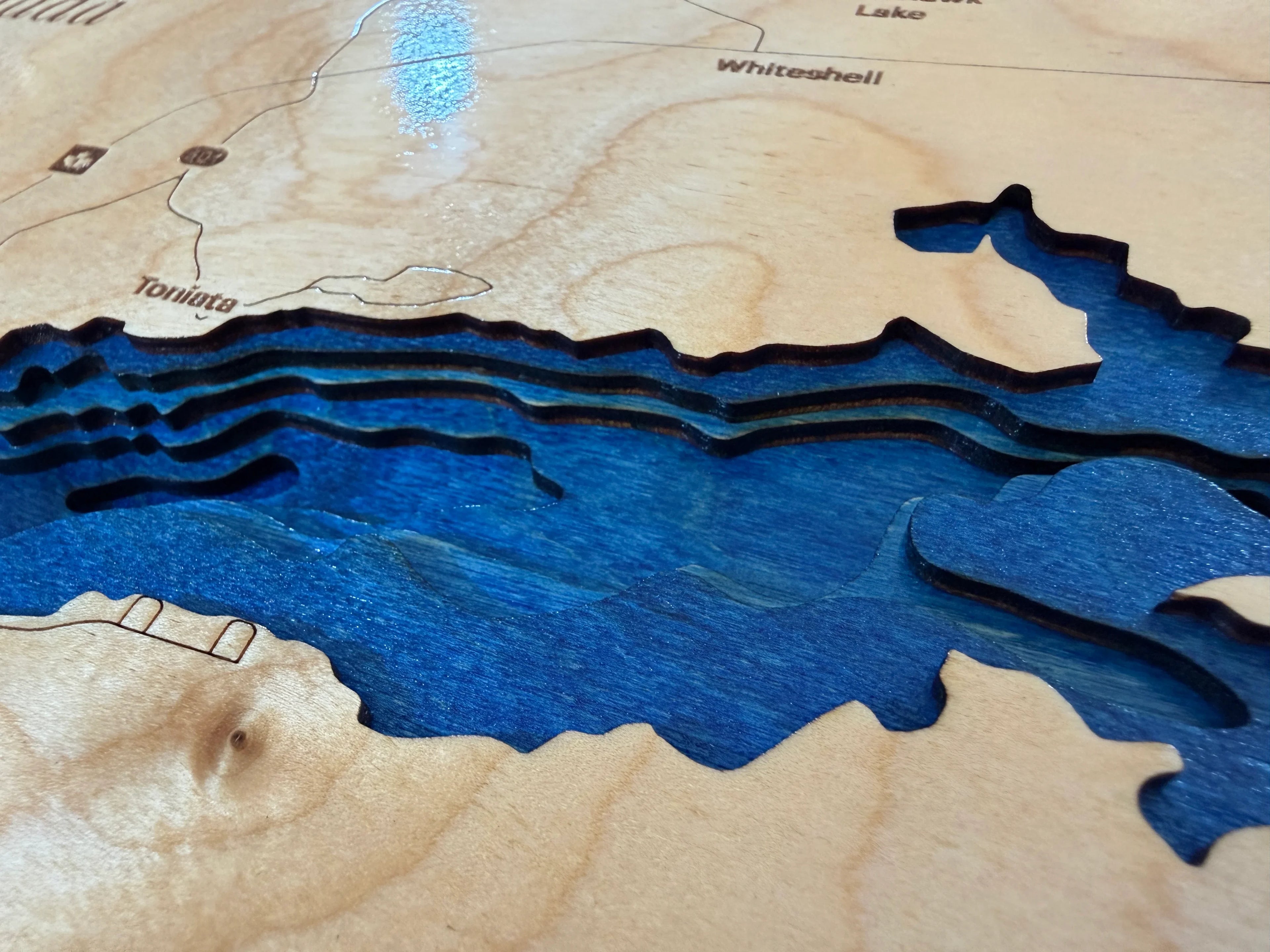 Layered wood lake map art with blue depth layers and engraved place names, handmade decorative wall decor