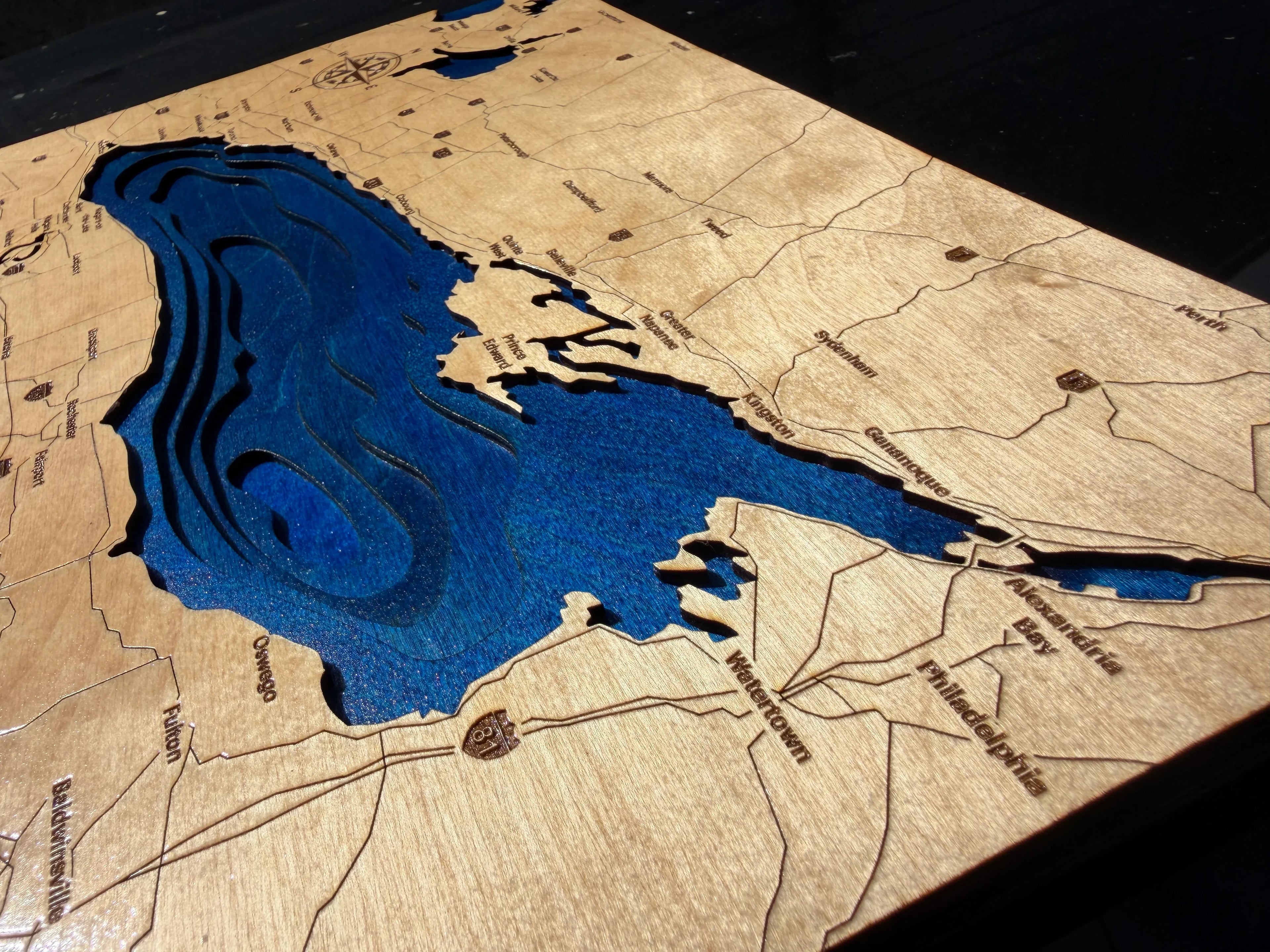 A 3D wooden map plaque of Lake Erie, featuring a natural wood grain surface with laser-engraved roads, cities, and a recessed blue resin lake area.