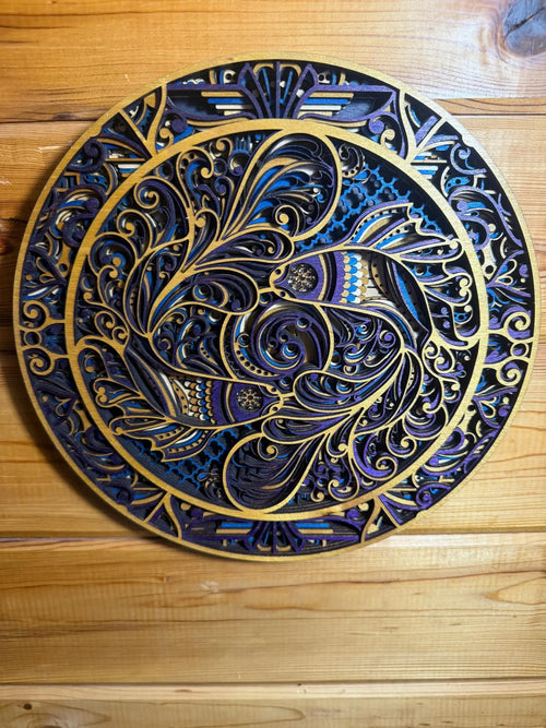 Intricate layered wood mandala with blue, purple, and gold swirls, displayed on rustic wood