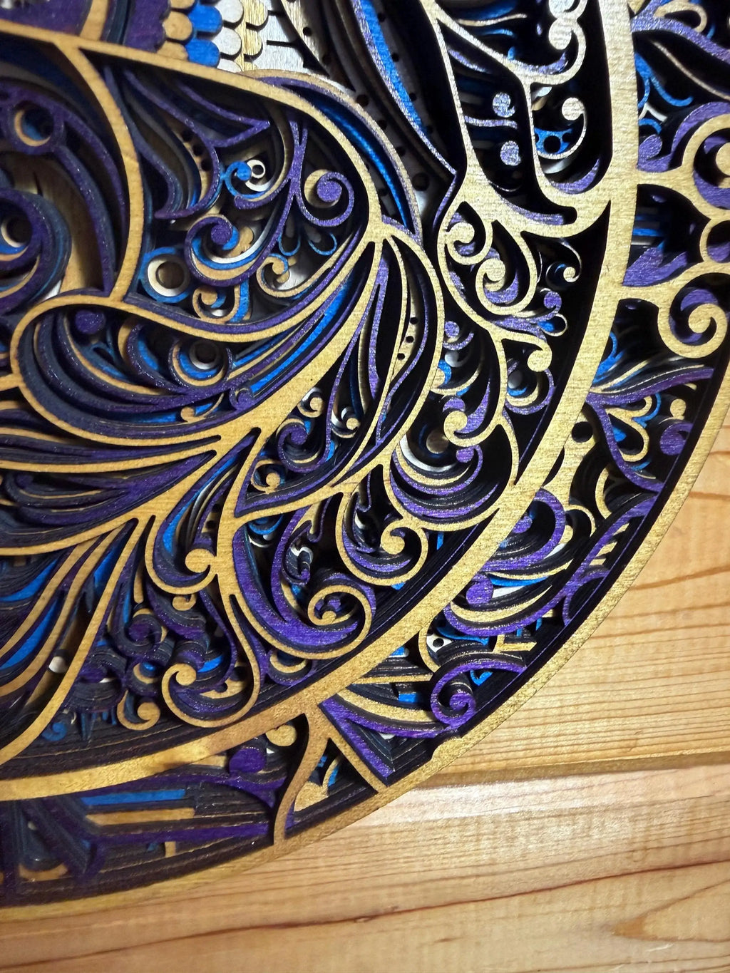 Layered wood mandala art with intricate blue, purple, and gold swirls, handcrafted laser-cut decor