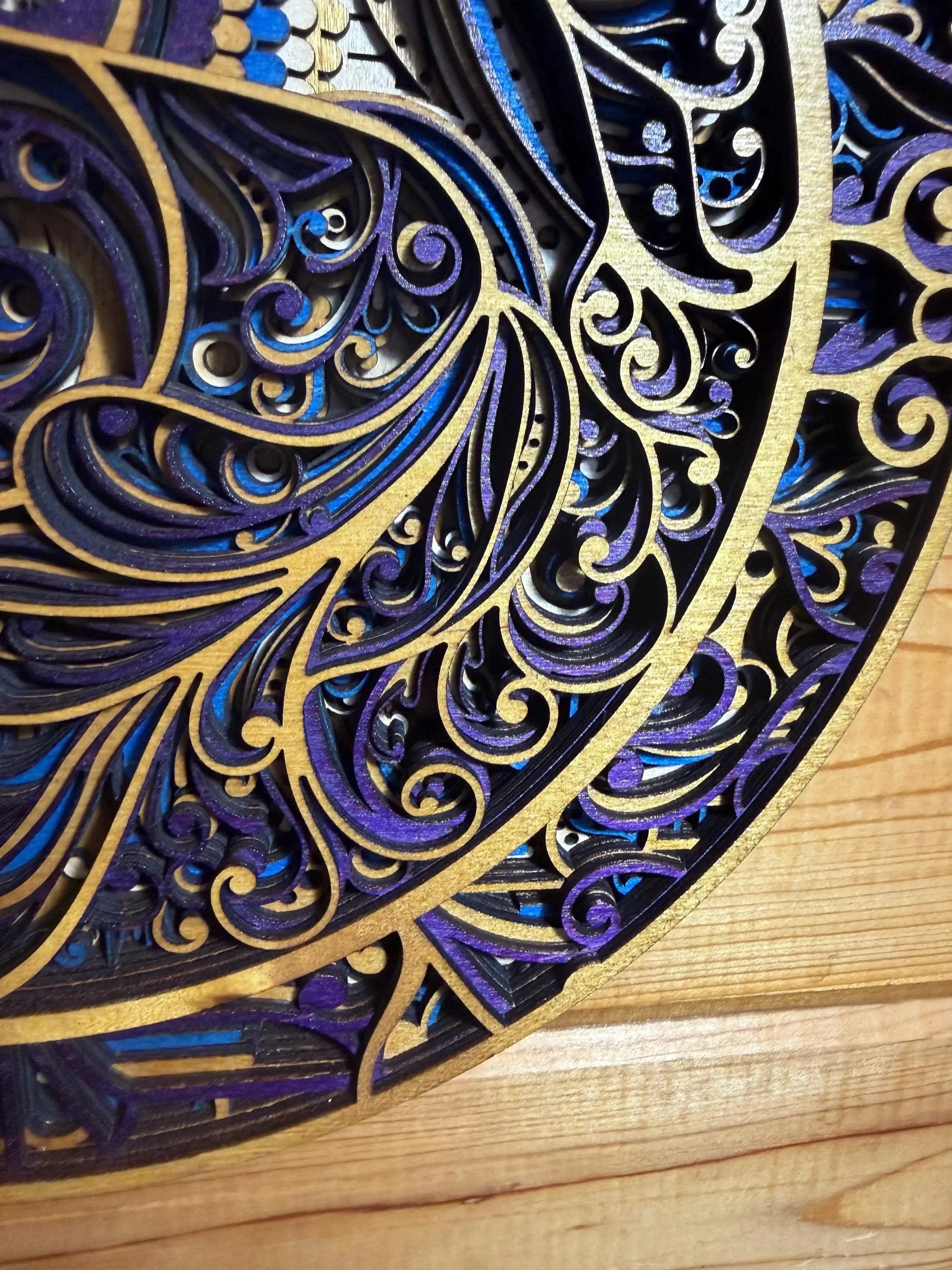 Layered wood mandala art with intricate blue, purple, and gold swirls, handcrafted laser-cut decor